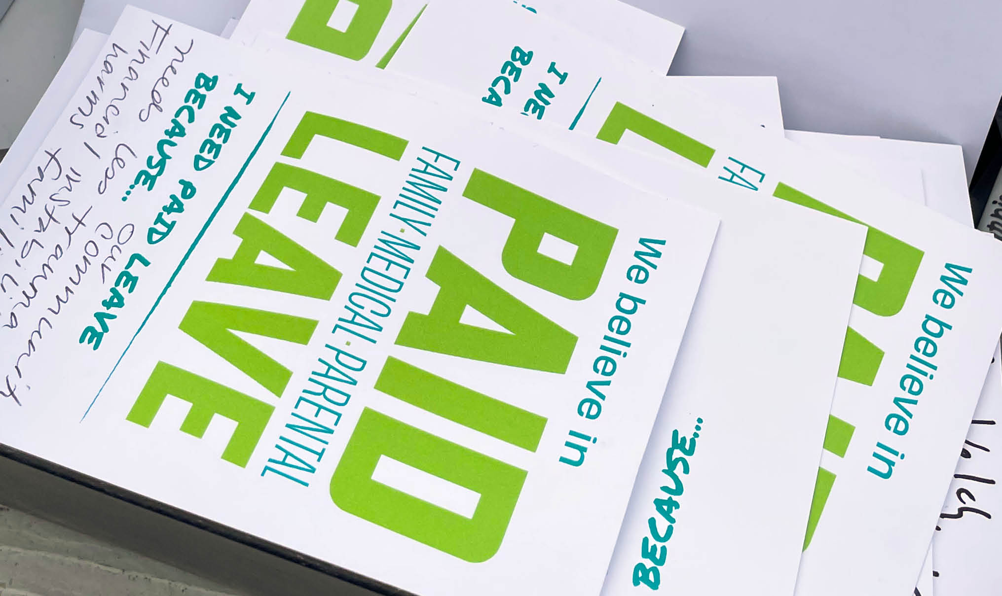 Close-up of a box of postcards with the We Believe in Paid Leave campaign logo on them and handwritten messages to congress members about the importance of paid leave.